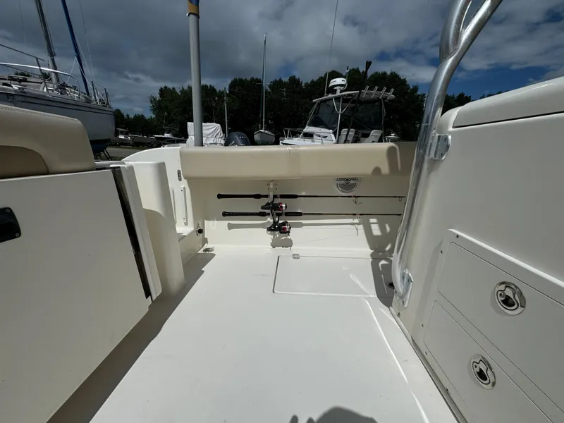 Slide: The Image of 2013 Cobia 296 Center Console boat interior with storage compartments and fishing rod holders. - 13