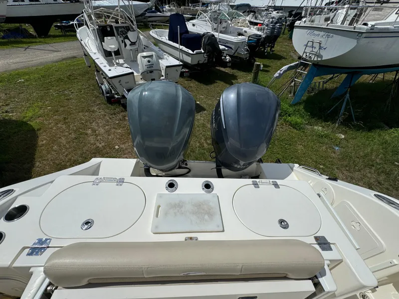 Slide: The Image of 2013 Cobia 296 Center Console boat with dual outboard motors, docked on grass. - 14
