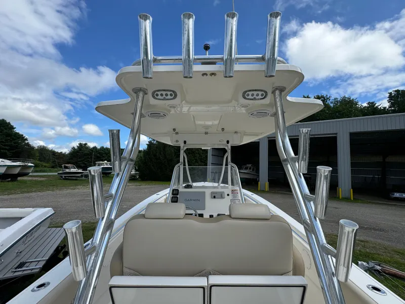 Slide: The Image of 2013 Cobia 296 Center Console boat with rod holders, parked outdoors under a blue sky. - 17