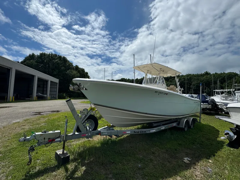Slide: The Image of 2013 Cobia 296 Center Console boat on trailer, parked outdoors under cloudy sky. - 3