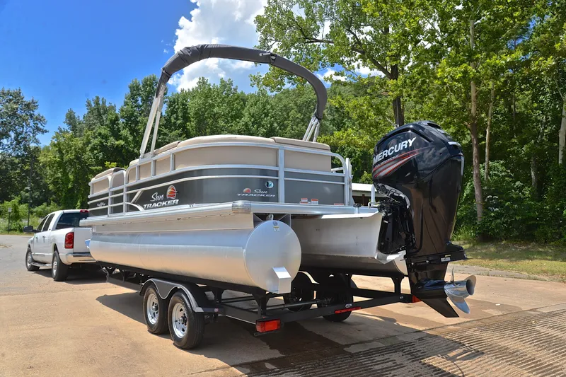 Slide: The Image of 2018 Sun Tracker Party Barge 20 pontoon boat on trailer, parked near trees. - 11
