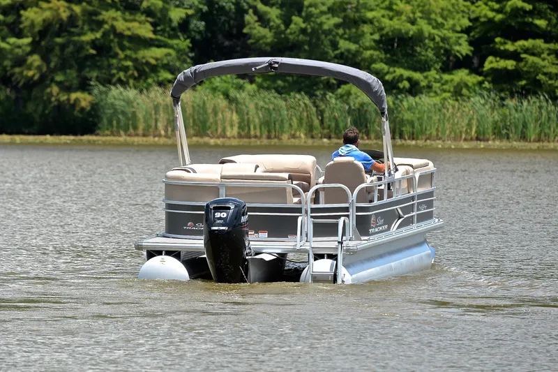 Slide: The Image of 2018 Sun Tracker Party Barge 20 pontoon boat cruising on a lake with lush greenery. - 7