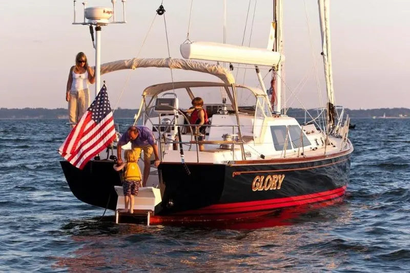 Slide: The Image of Family enjoying a 2011 Tartan 4700 sailboat named "Glory" on the water. - 2