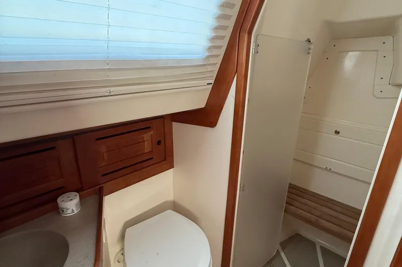 Slide: The Image of 2011 Tartan 4700 yacht bathroom with wooden cabinets and a compact toilet. - 56