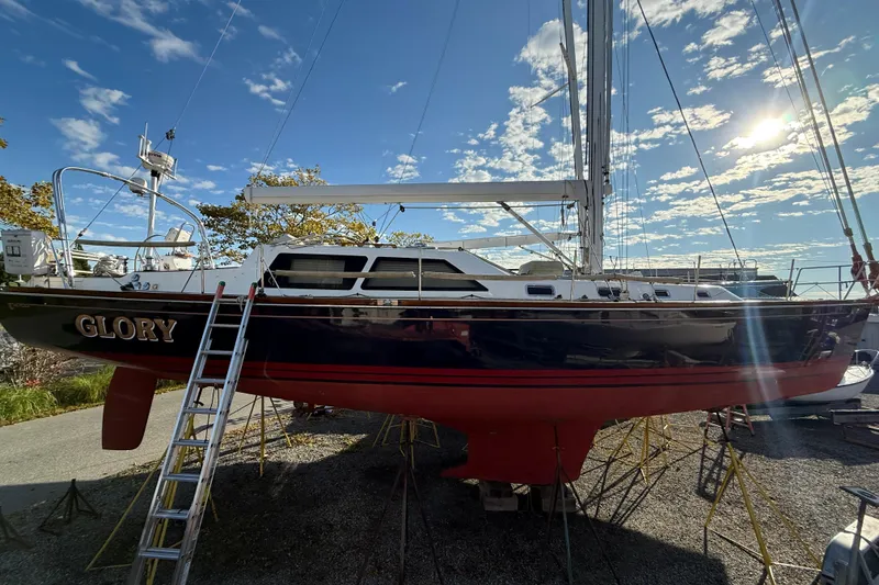 Slide: The Image of Sailboat Tartan 4700, 2011 model, named "Glory" on dry dock under a sunny sky. - 6