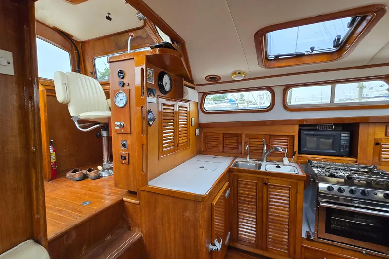 Slide: The Image of 1981 Cheoy Lee 43 Pilot House interior with wooden cabinetry, kitchen, and helm seat. - 10