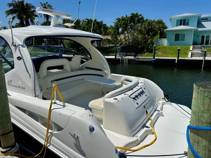 Slide: The Image of 2004 Sea Ray 420 Sundancer yacht docked by waterfront home, sunny day. - 2