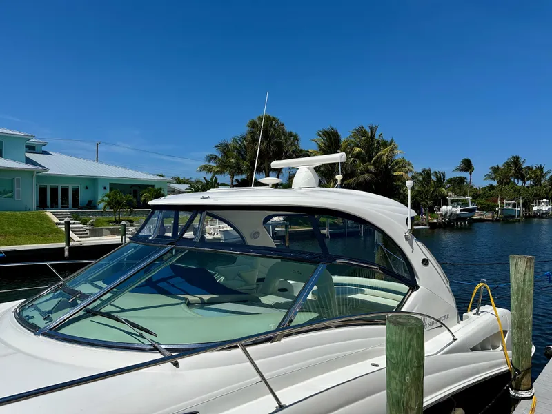 Slide: The Image of 2004 Sea Ray 420 Sundancer yacht docked by a waterfront home under clear blue skies. - 3