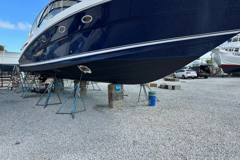 Slide: The Image of 2004 Sea Ray 420 Sundancer yacht on stands in a boatyard, gravel ground. - 30