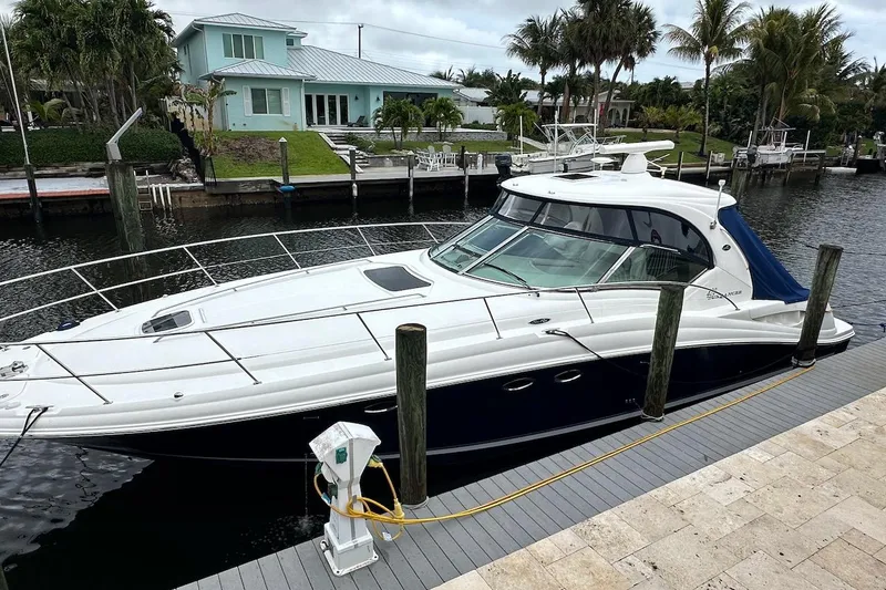 Slide: The Image of 2004 Sea Ray 420 Sundancer yacht docked by waterfront home, surrounded by palm trees. - 31