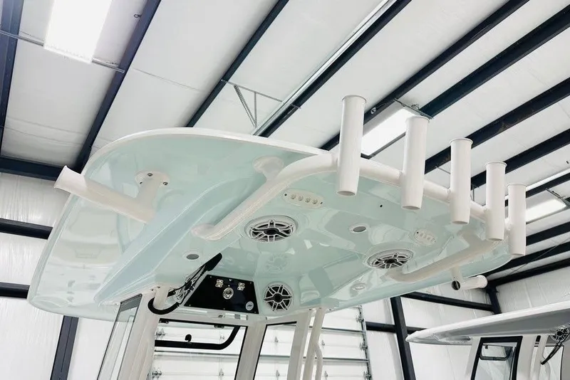 Slide: The Image of 2026 Sportsman Open 262 Center Console boat with rod holders and speakers in a warehouse. - 6