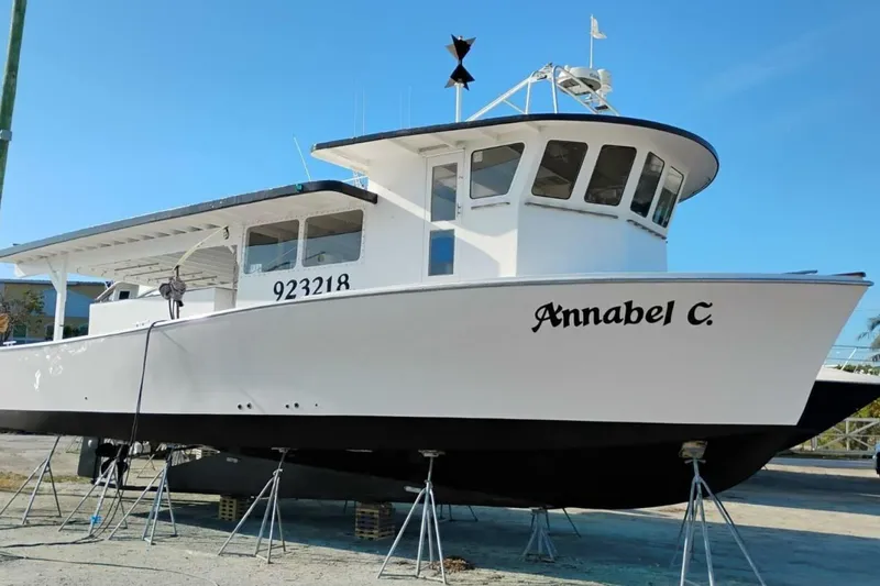 The Image of 1987 Monroe Custom 52 boat "Annabel C." on stands, clear sky background. - 1