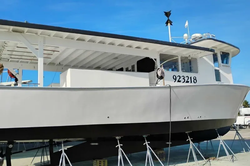 Slide: The Image of 1987 Monroe Custom 52 boat on stands, hull number 923218, under clear blue sky. - 3