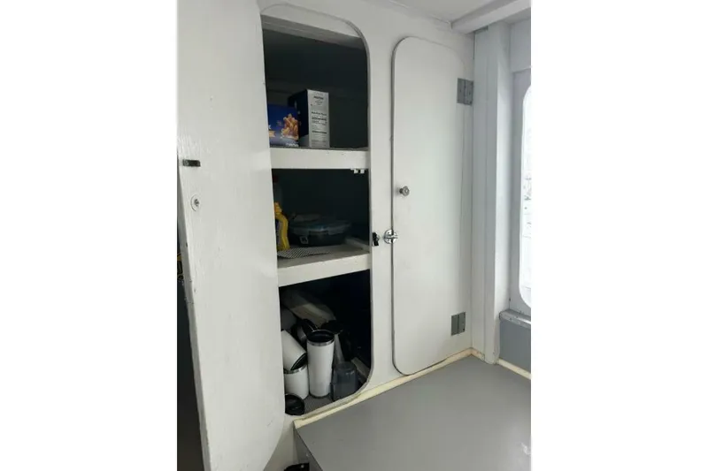 Slide: The Image of White storage cabinet with open door, shelves, and various items inside, in a 1987 Monroe Custom 52. - 30