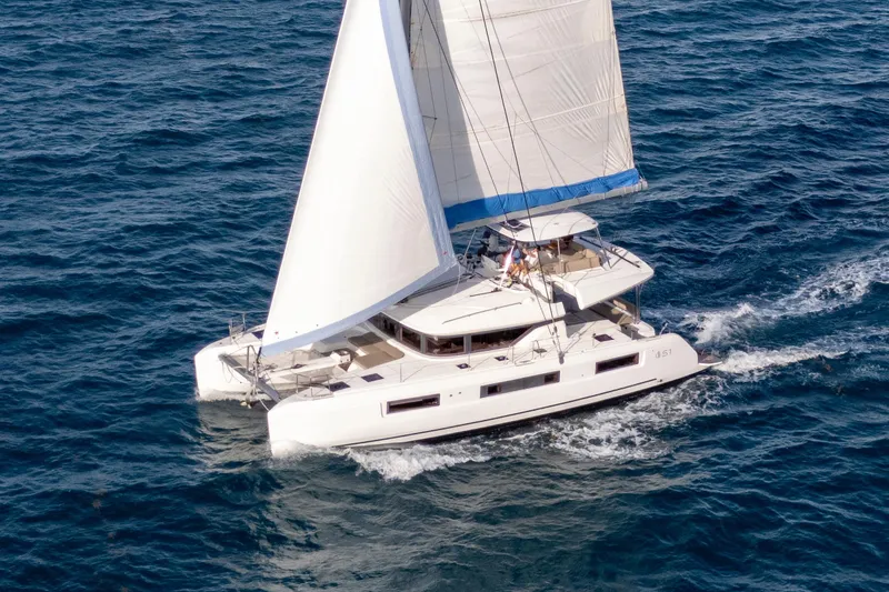 The Image of 2024 Lagoon 51 catamaran sailing on open sea with white sails. - 0