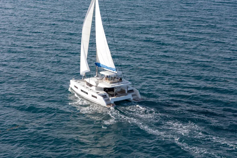 Slide: The Image of 2024 Lagoon 51 catamaran sailing on open sea with white sails. - 10
