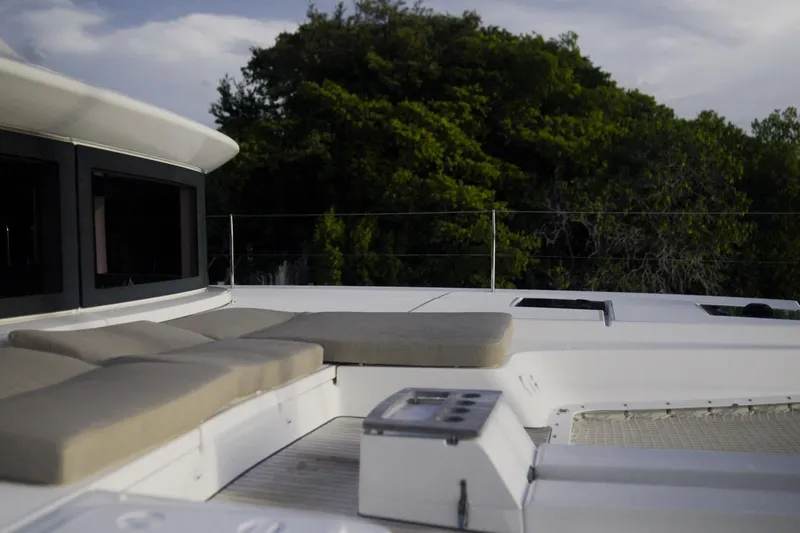 Slide: The Image of Luxurious 2024 Lagoon 51 yacht deck with cushioned seating, surrounded by lush greenery. - 20