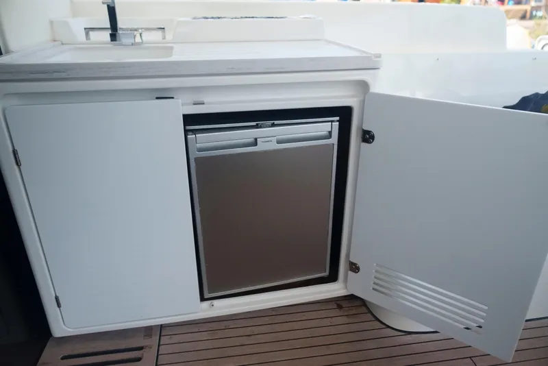 Slide: The Image of 2024 Lagoon 51 yacht kitchenette with open cabinet and compact fridge. - 27