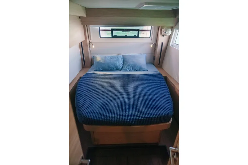 Slide: The Image of 2024 Lagoon 51 yacht bedroom with blue bedding and modern design. - 36