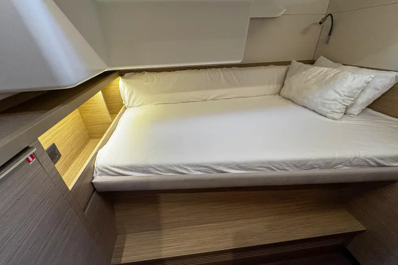 Slide: The Image of 2024 Lagoon 51 yacht interior cabin with cozy bed and ambient lighting. - 43