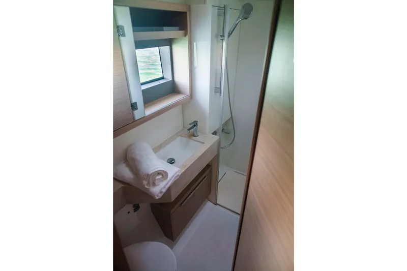 Slide: The Image of 2024 Lagoon 51 yacht bathroom with modern sink, shower, and window view. - 45