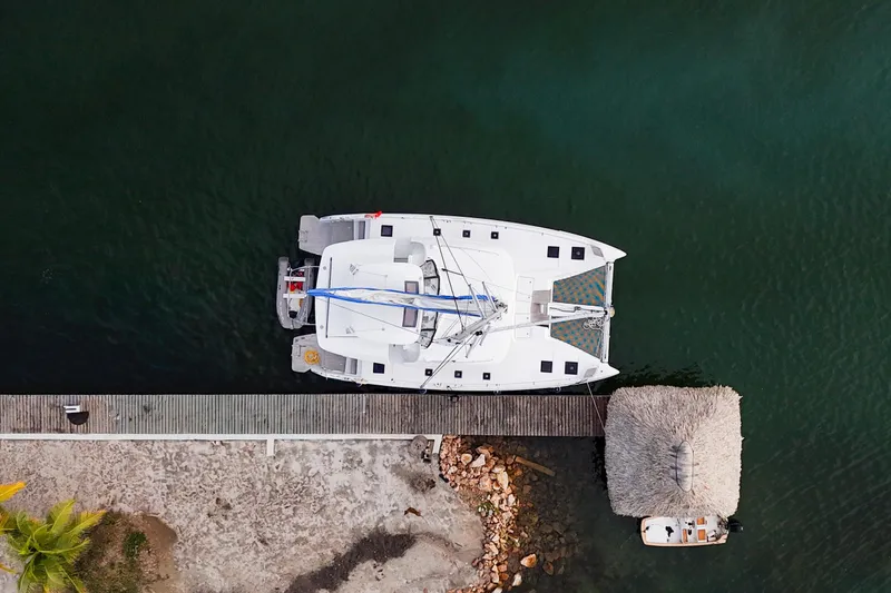 Slide: The Image of Aerial view of 2024 Lagoon 51 catamaran docked by a thatched-roof hut. - 57