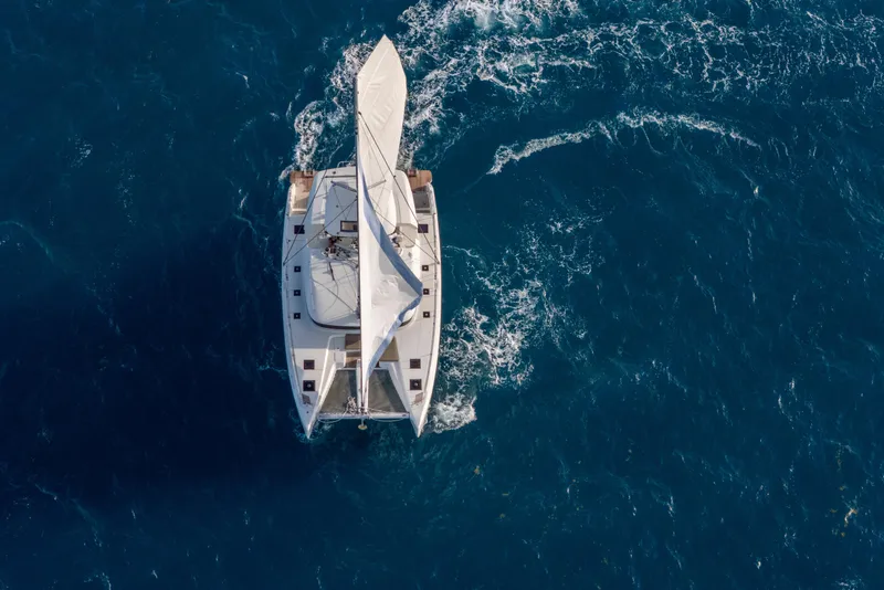 Slide: The Image of Aerial view of 2024 Lagoon 51 sailing catamaran navigating through blue ocean waters. - 61