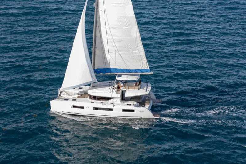 Slide: The Image of 2024 Lagoon 51 sailing catamaran cruising on open sea with full sails. - 7