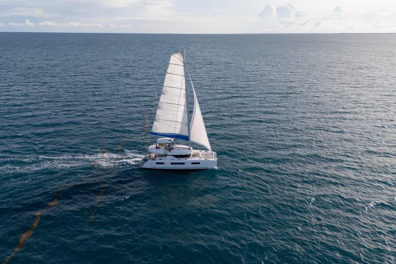 Slide: The Image of 2024 Lagoon 51 catamaran sailing on open ocean under clear skies. - 8