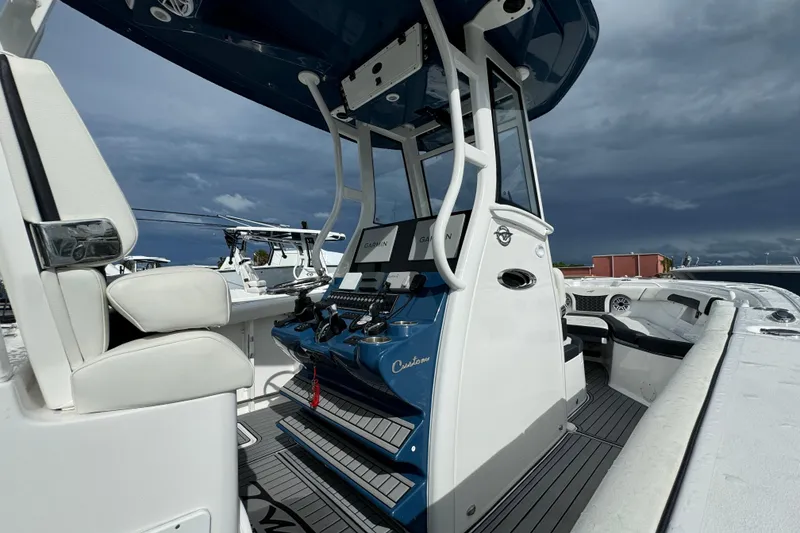 Slide: The Image of 2024 Tidewater 292 CC Adventure boat interior with helm and seating under cloudy sky. - 15