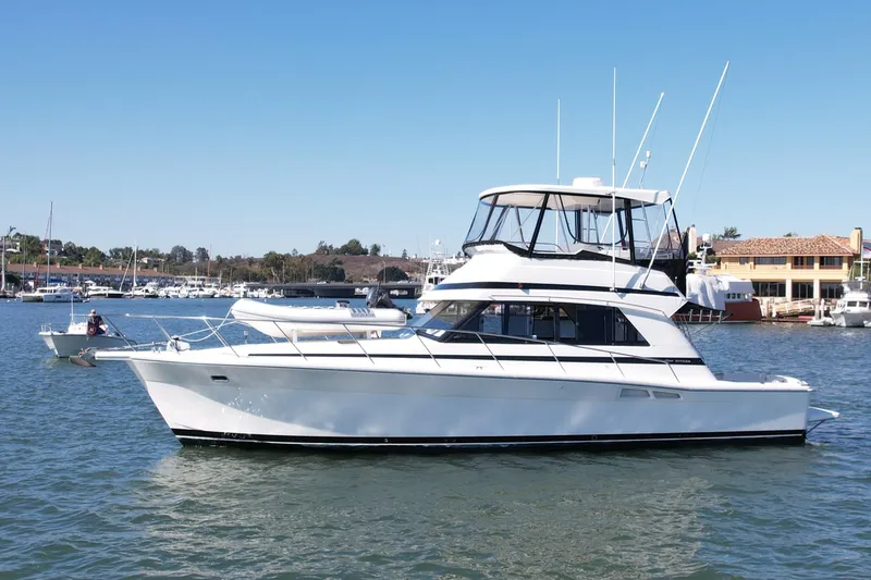 The Image of 1998 Riviera 43 Open Flybridge yacht on calm water, marina background. - 0
