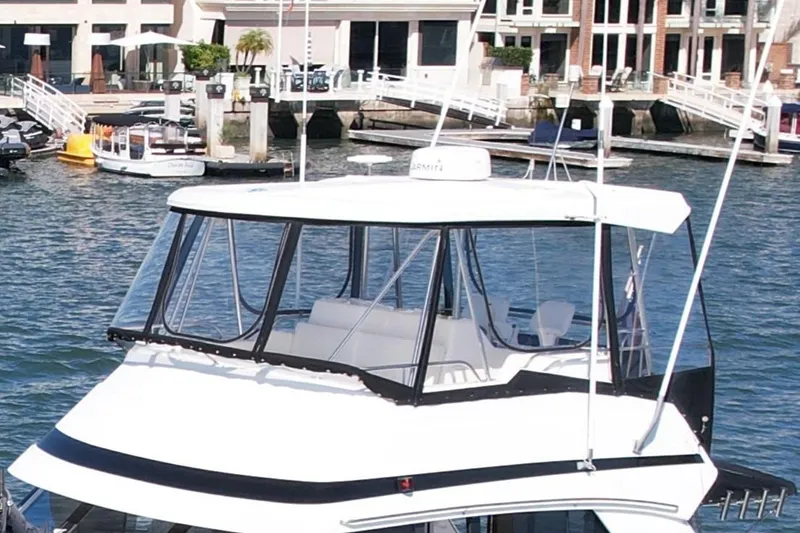Slide: The Image of 1998 Riviera 43 Open Flybridge yacht docked in a marina with waterfront buildings. - 11