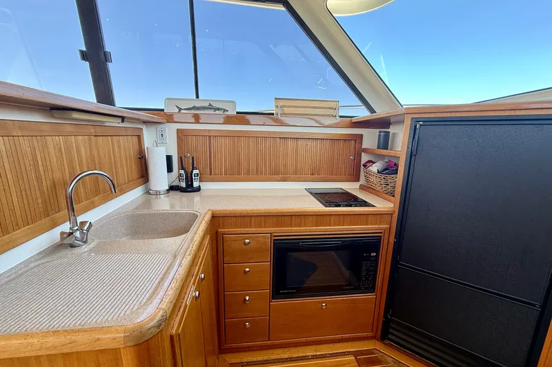 Slide: The Image of 1998 Riviera 43 Open Flybridge yacht kitchen with sink, stove, and microwave. - 17