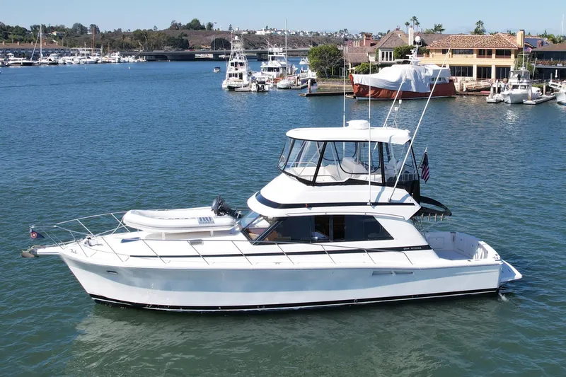 Slide: The Image of 1998 Riviera 43 Open Flybridge yacht on calm waters near a marina. - 2