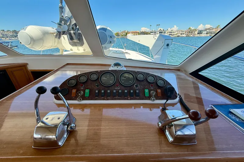 Slide: The Image of 1998 Riviera 43 Open Flybridge helm with controls and gauges, overlooking marina view. - 23