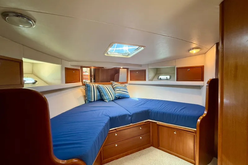 Slide: The Image of Cozy cabin interior of 1998 Riviera 43 Open Flybridge with blue bedding and wooden storage. - 29