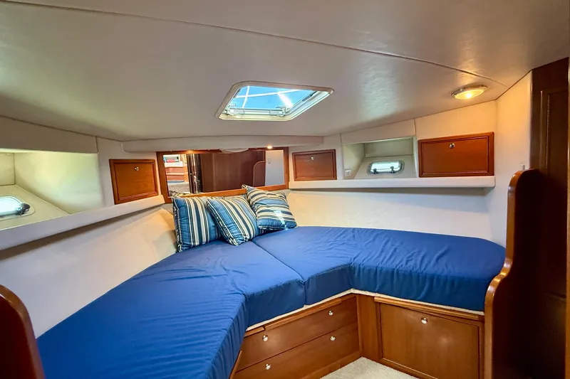 Slide: The Image of 1998 Riviera 43 Open Flybridge cabin with blue bedding and wooden storage cabinets. - 30