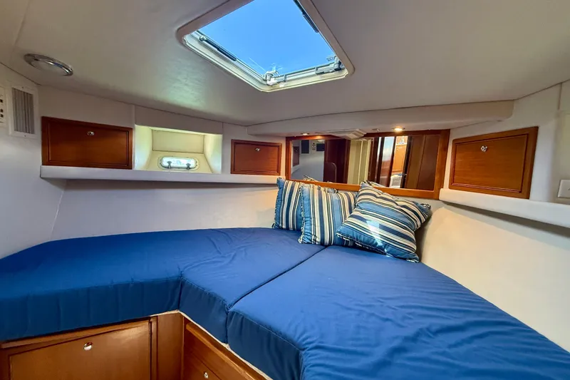 Slide: The Image of Cozy cabin interior of 1998 Riviera 43 Open Flybridge with blue bedding and striped pillows. - 31