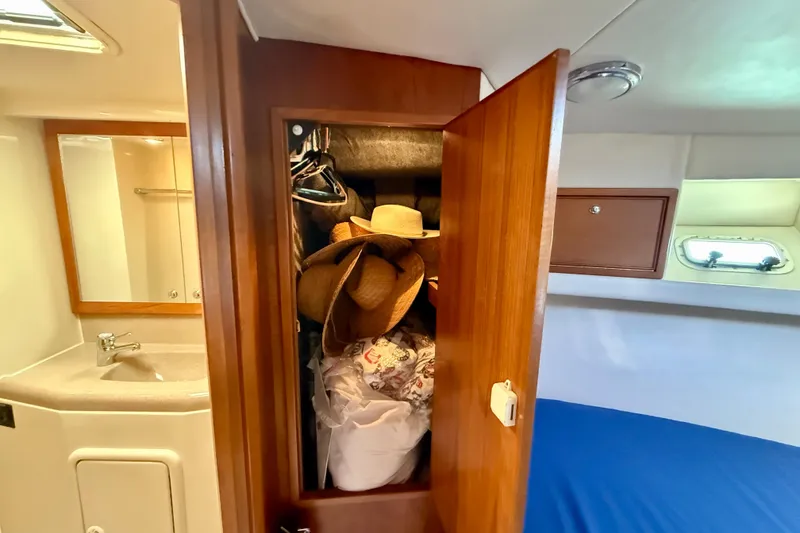 Slide: The Image of 1998 Riviera 43 Open Flybridge cabin with open closet, hats, and bathroom sink. - 33