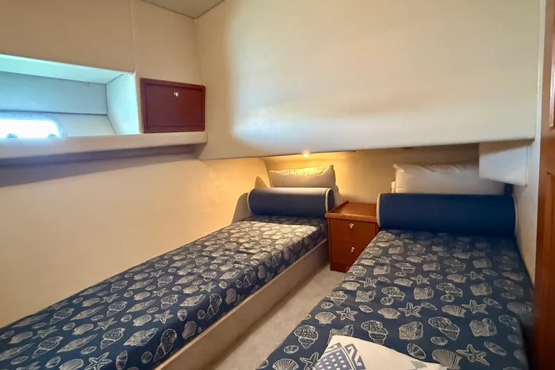 Slide: The Image of 1998 Riviera 43 Open Flybridge cabin with twin beds, nautical-themed bedding, and wooden cabinetry. - 39