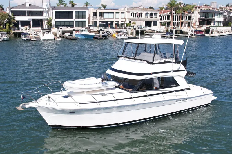 Slide: The Image of 1998 Riviera 43 Open Flybridge yacht cruising near waterfront homes. - 5