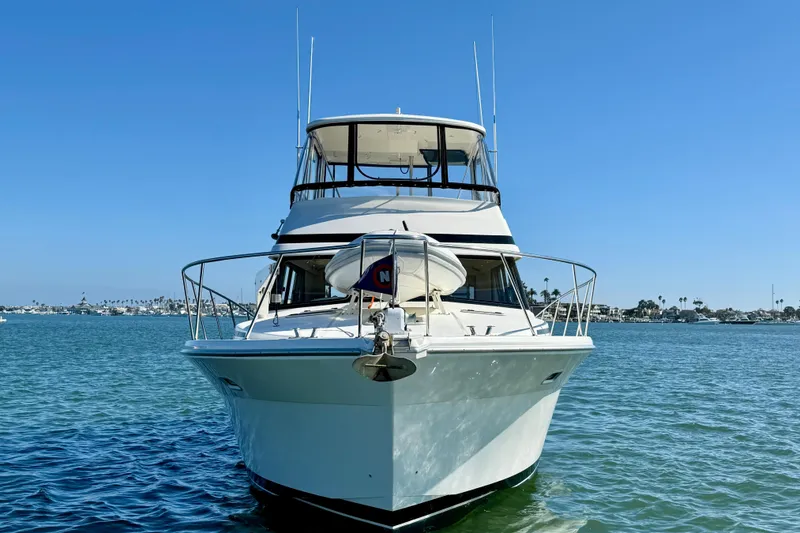 Slide: The Image of 1998 Riviera 43 Open Flybridge yacht on calm water under clear blue sky. - 7