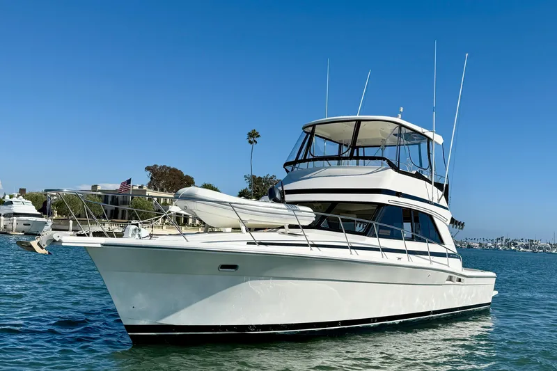 Slide: The Image of 1998 Riviera 43 Open Flybridge yacht on calm water under clear blue sky. - 8