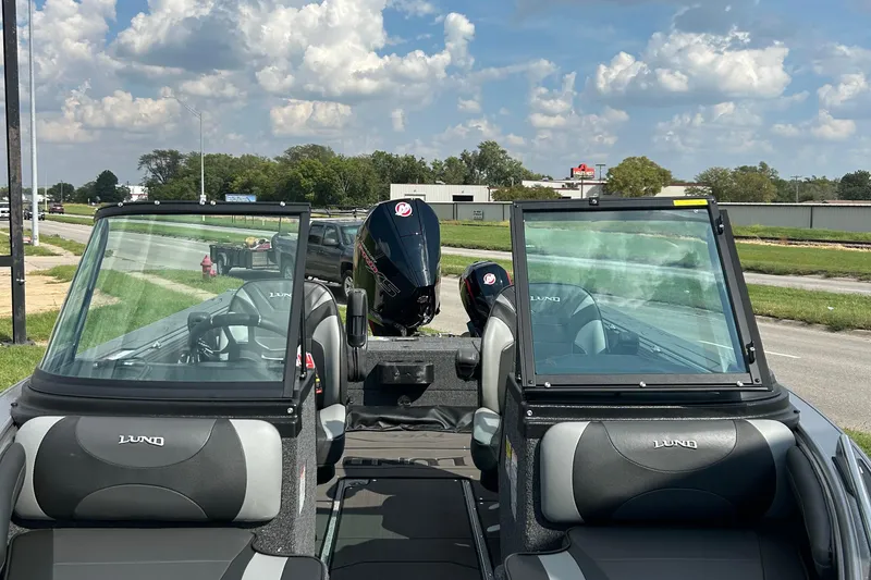 Slide: The Image of 2026 Lund 1975 Tyee boat interior with dual windshields and outboard motor, parked roadside. - 21