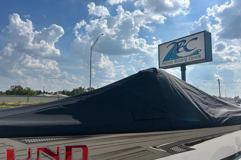 Slide: The Image of Covered Lund 1975 Tyee boat at Premier Boating Center, 2026 model, under cloudy sky. - 23