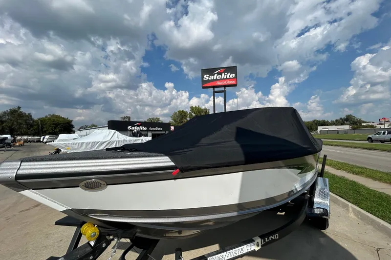 Slide: The Image of 2026 Lund 1975 Tyee boat covered, parked near Safelite AutoGlass under a cloudy sky. - 24