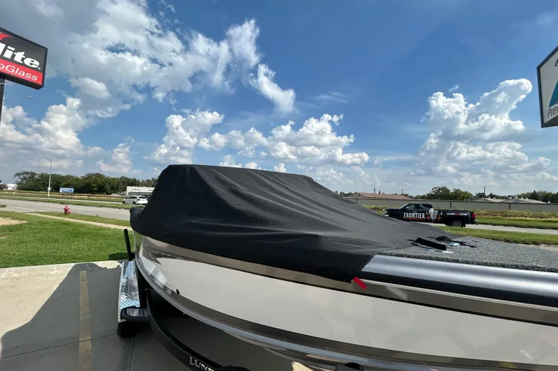 Slide: The Image of 2026 Lund 1975 Tyee boat covered, parked outdoors under a partly cloudy sky. - 26