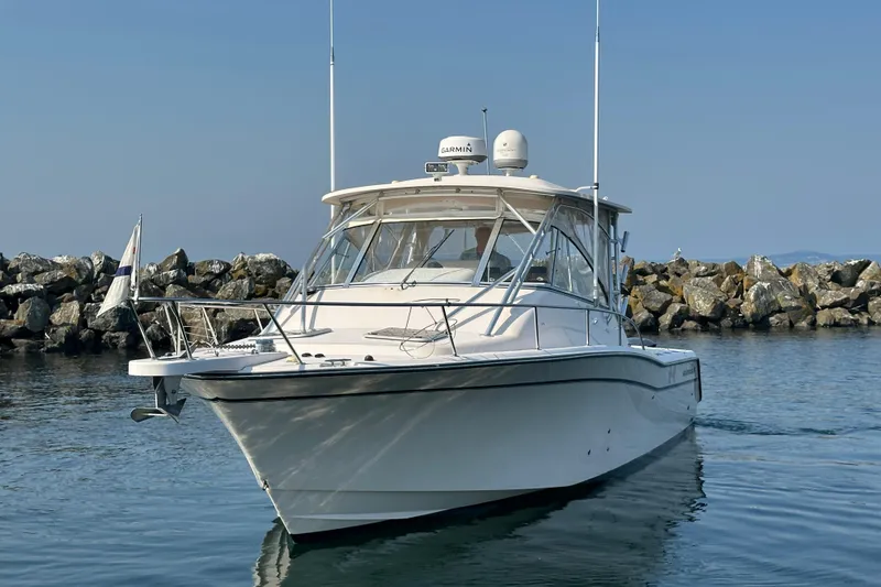 Slide: The Image of 2008 Grady White Express boat navigating near rocky shoreline under clear sky. - 1