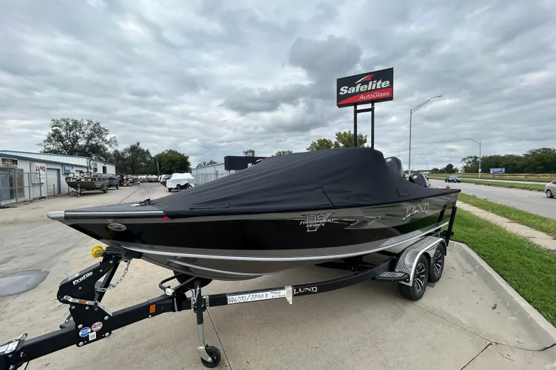 Slide: The Image of 2026 Lund 1975 Pro-V boat with cover on trailer, parked near Safelite AutoGlass sign. - 30