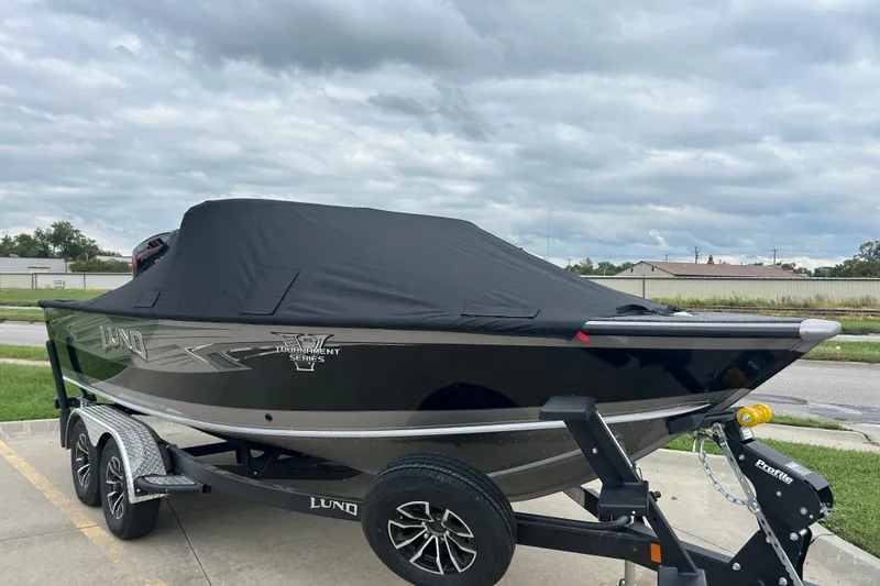 Slide: The Image of 2026 Lund 1975 Pro-V boat with cover on trailer, parked outdoors under cloudy sky. - 36